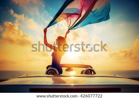 Silhouette of beautiful woman relaxing on the beach. Person having fun in cabriolet against blue sky background. Summer vacation and travel concept