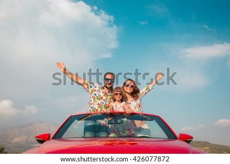 Happy family travel by car in the mountains. People having fun in red cabriolet. Summer vacation concept