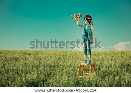 Happy kid playing. Child with toy airplane. Kid having fun outdoors. Child in summer field. Travel and vacation concept. Imagination and freedom concept
