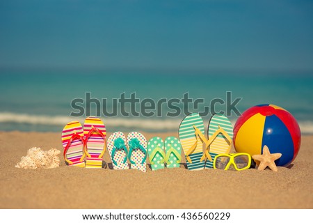 Flip-flops on sandy beach against blue sea and sky background. Summer vacation concept