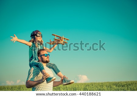 Happy family outdoors. Child playing with father. Dad and son having fun in summer field. Man carrying kid. Child with toy airplane. Kid pretend to be pilot. Travel, vacation and freedom concept