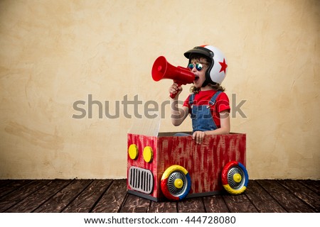 Child driving a car made of cardboard box. Kid having fun at home. Travel and summer vacation concept