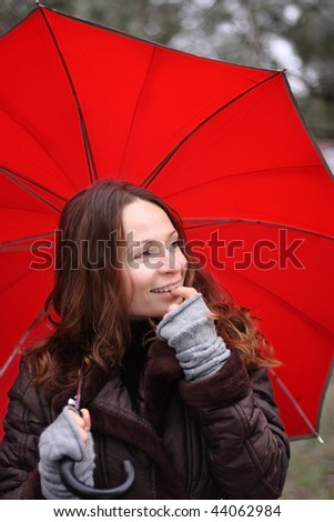 Young woman under a red umbrella in autumn