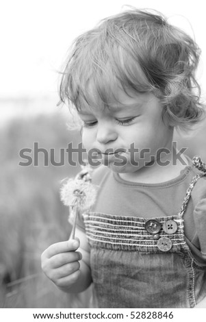 Black and white photo of the little girl blowing on dandelion - shallow depth of field