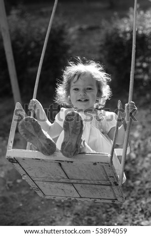 Child playing on the swings - black and white photo with yellow filter effect, shallow depth of field, back lighting