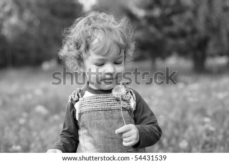 Black and white photo of kid blowing on dandelion - shallow depth of field