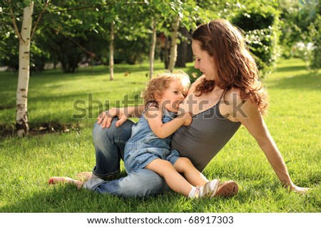 Cute woman nurses her little child in park