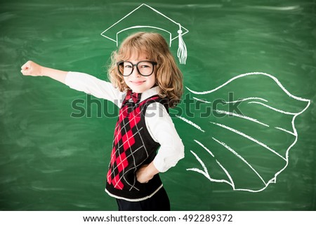 Superhero school child in class. Happy kid against green blackboard. Knowledge is power concept
