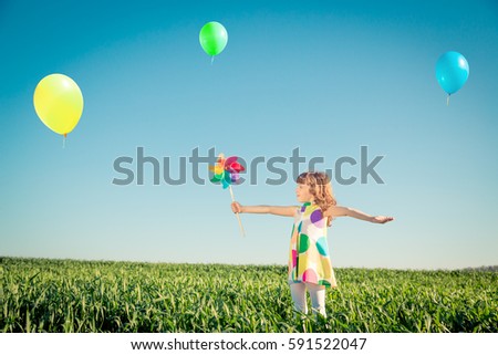 Happy child outdoors against blue sky background. Kid having fun in green spring field. Freedom and imagination concept