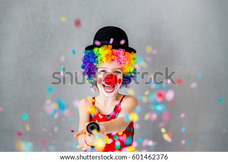 Let\'s party!! Funny kid clown playing at home. Child shooting party popper confetti. 1 April Fool\'s day concept