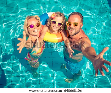 Happy family having fun on summer vacation. Father, mother and child playing in swimming pool. Active healthy lifestyle concept