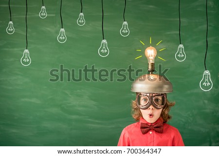 Bright idea! Funny child in classroom. Kid with toy virtual reality headset in class. Success, idea and innovation technology concept. Back to school