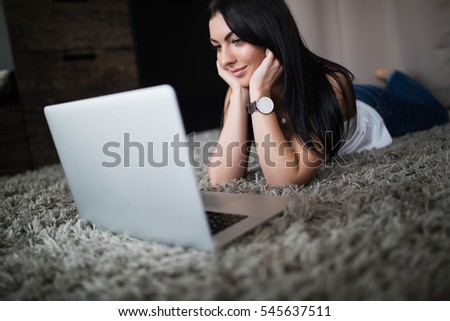 brunette woman watch movie on laptop at home on carpet