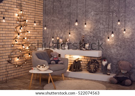 Modern interior of living room. Creative Christmas tree, contemporary fireplace and large gray armchair in loft interior design apartment.