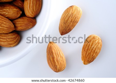 almond nut in white cup and almond on white background. top eye view.