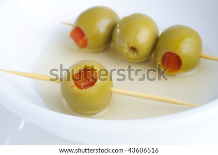 green olives stuffed with pepper on a wooden toothpick on the white background