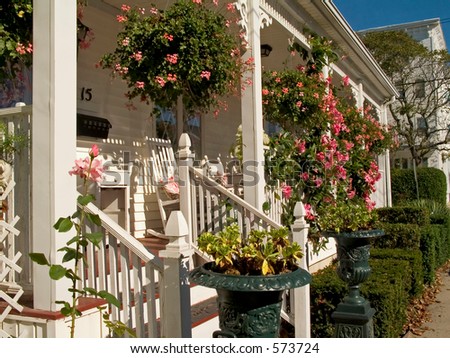 This is a shot of a white porch decorated nicely with some hanging flower baskets.