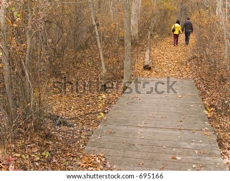 This is a shot of a couple taking a Fall hike on a nature trail.