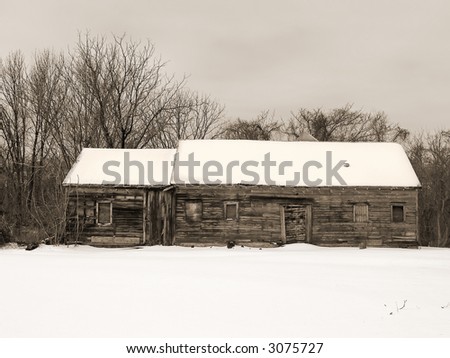 A sepia toned photo of an old wooden cabin in the snow.