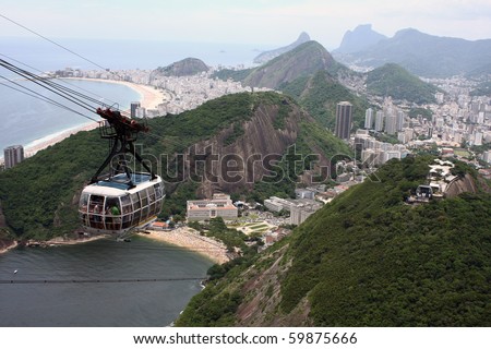 Cable car descending from Sugar Loaf Mountain; view of Copacabana Beach in the back.