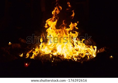 Flames and smoke fill this image of a ceremonial fire during a mayan ritual with a candle in each direction.