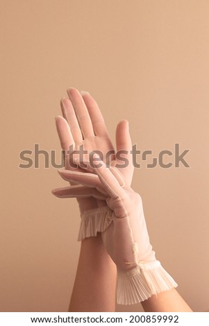 Image of woman\'s forearms and hands modeling vintage sheer see through gloves.