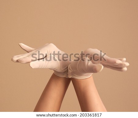 A woman\'s hands and forearms are shown as she models a vintage pair of formal white glove. THe back of her wrists are together and her hands and fingers are facing opposite directions.