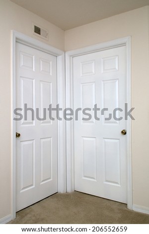 View of two white interior doors closed in carpeted room.