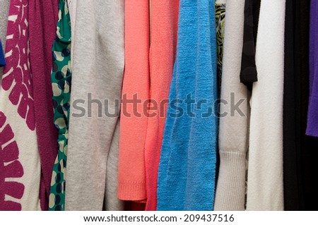 Close up of woman\'s clothing hanging in closet, showing various materials and colors
