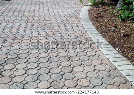 A brick driveway in bonita springs florida composed of octagon and square shaped bricks stretches off into the distance bordered with white bricks.