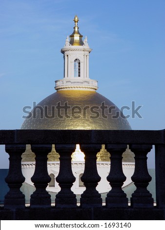 the golden dome of the state house with cement pillars in the foreground, dome is at eye level
