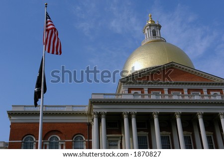 Looking up at the Massachusetts State House a deep blue sky is in the background and both the american flag and the pow/mia flags are in the fore