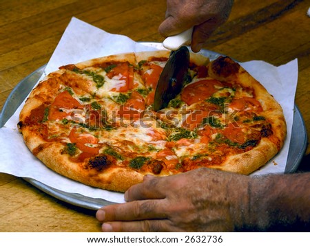 freshly baked pizza pie being sliced by chef