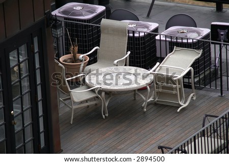 roofdeck with chairs, one is overturned, french doors on left,air handlers behind chairs