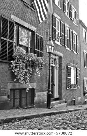 Famous Acorn Street, america\'s most photographed area in the Beacon Hill area of Boston Massachusetts, showing gas light, cobblestone road, shutters. american flag