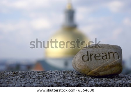 dream rock sits on cement ledge with the massachusetts state house in the background,representing dreams of success and achievement