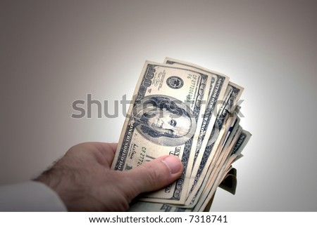 man holding out large amount of cash wearing white dress shirt, with spot light on the money