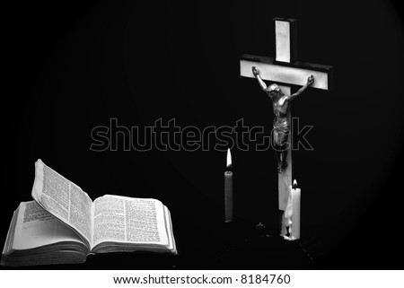 stark black and white image of a prayer crucifix with two candles set out before a bible open to the book of Matthew