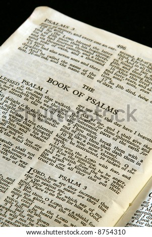 bible series, detail of an old antique holy bible against a black background open to the book of psalms old testament