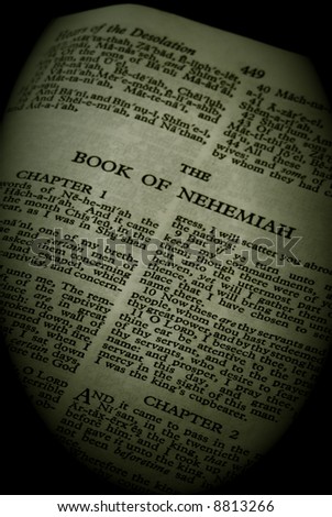 bible series, detail of an old antique holy bible against a black background open to the book of nehemiah old testament finish in sepia