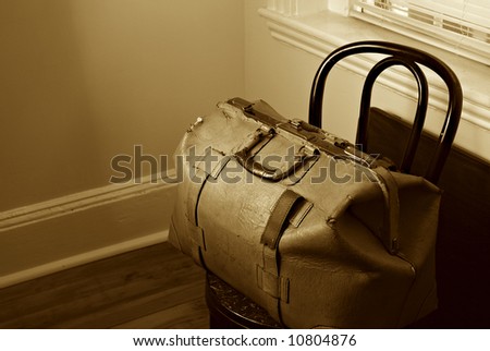 old cracked and broken leather traveling bag on old chair set near window