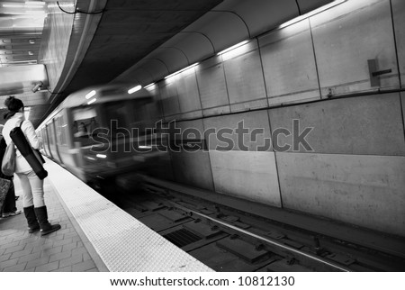 motion is blurred as train enters the station at the harvard square subway stop, woman with bag waits for train, cambridge, massachusetts