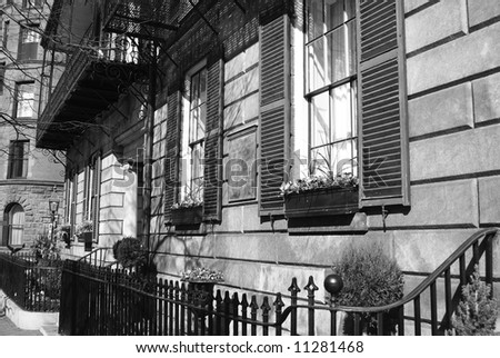 shuttered windows on an old building with flower boxes and wrought iron fence in black and white