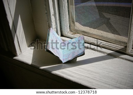 old passport sitting on window sill in the sunshine of an old abandoned house