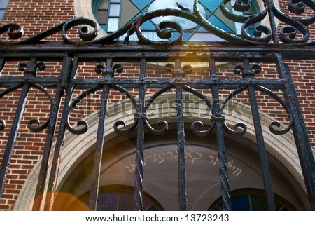 old iron synagogue gate in front of arched stained windows with star of david and artistic use of lens flare in beacon hill boston massachusetts