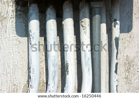 row of old painted electrical conduits on outside of building