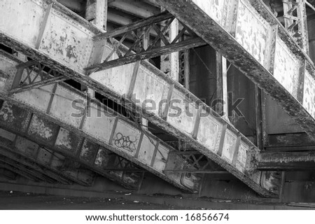 view of the structure of bridge showing cross bars rivets rust and peeling paint
