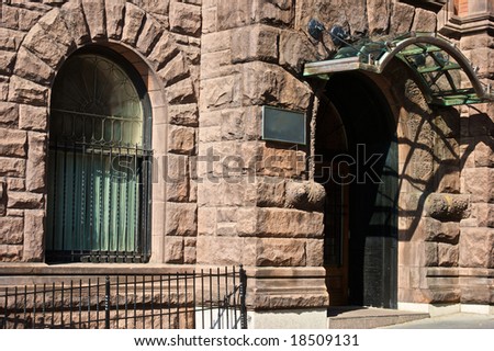 old stone building with arched window and entry and blank sign