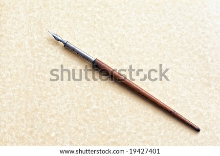 old fashioned ink dip pen for writing or drawing on parchment paper background