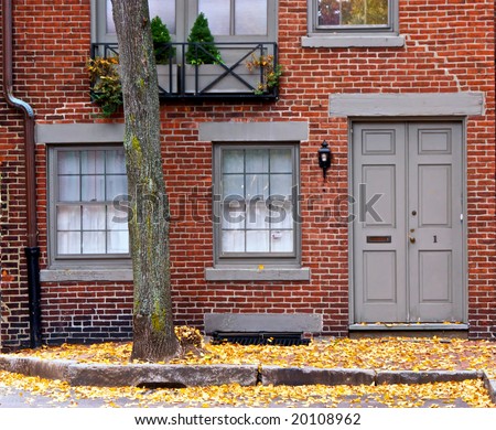 cute little brick home with grey door and windows on an autumn day
